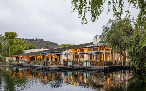 a building with tables and umbrellas outside by the water