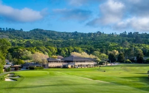 a large green field with a building and trees in the background