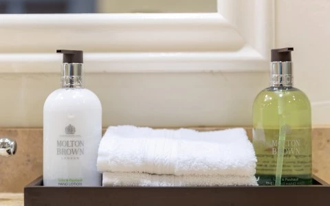 a white towel and a bottle of lotion on a shelf